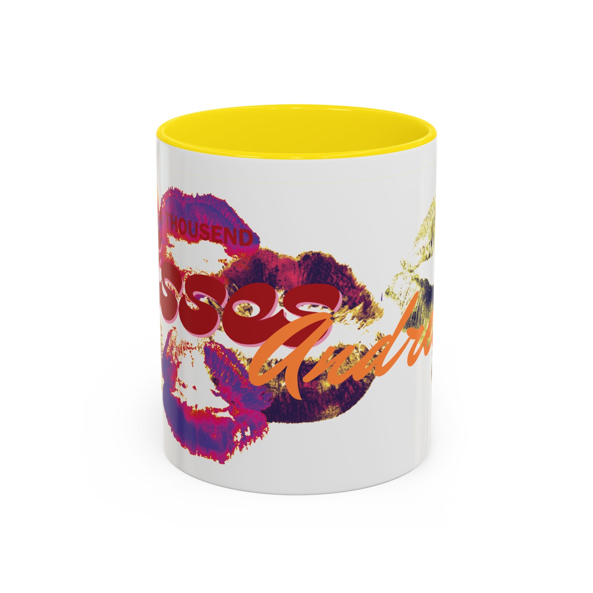 The Kiss Print Accent Coffee Mug — Personalized 'A Thousand Kisses' Pop-Art Lip Design (11oz) features a white ceramic body, yellow interior, colorful lipstick prints, bold red/orange text, and is dishwasher safe for easy cleaning.