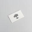 A white card from Example product rests on a light gray surface, featuring a simple black illustration of a tree with detailed branches and roots.