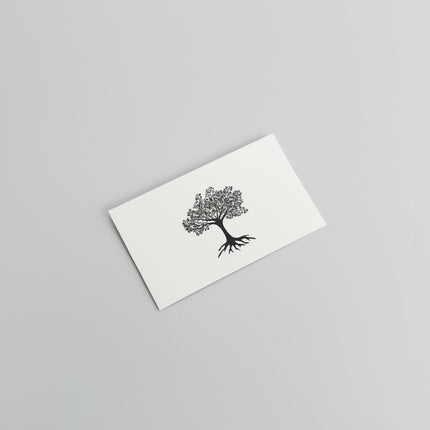 A white card from Example product rests on a light gray surface, featuring a simple black illustration of a tree with detailed branches and roots.